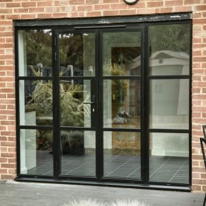 An exterior shot of Crittall hinged double external doors against a brick wall. 